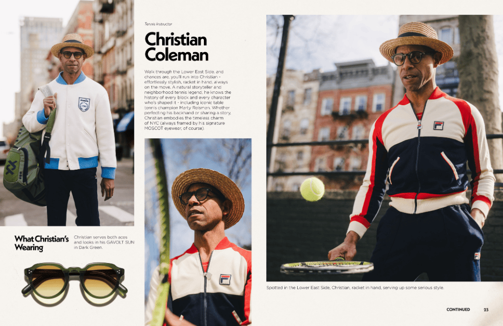 Christian Coleman in a tennis jacket and hat on a street, holding a tennis racket and wearing moscot glasses.