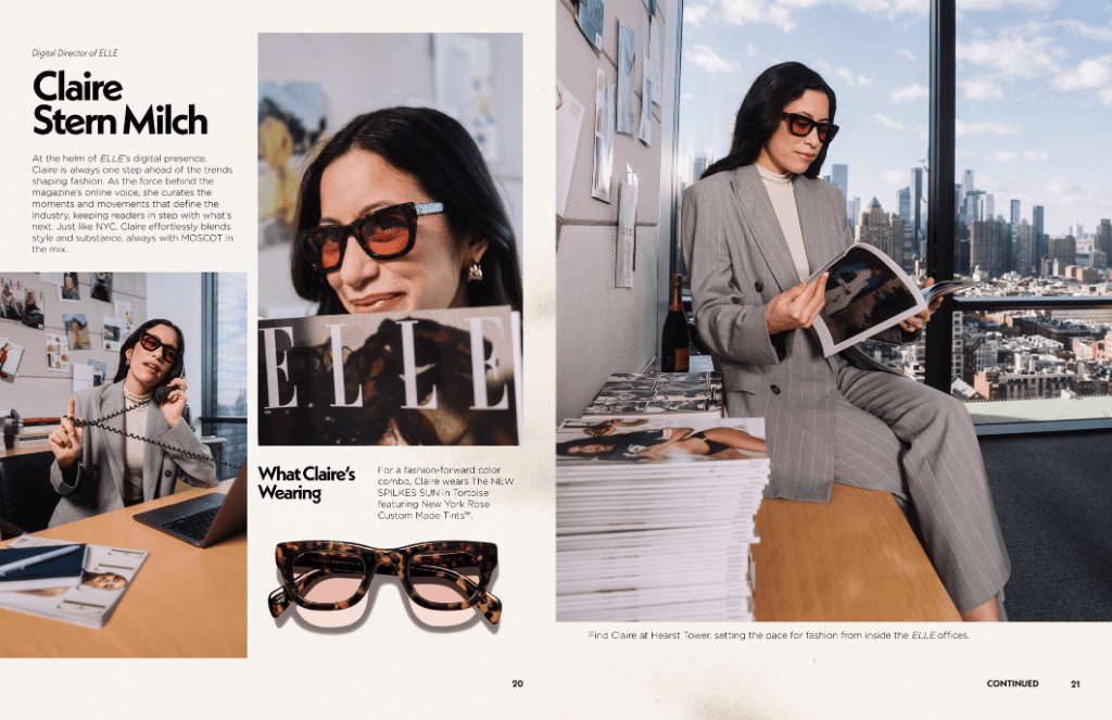 Woman in a suit wearing sunglasses, holding a magazine, in an office with city views.
