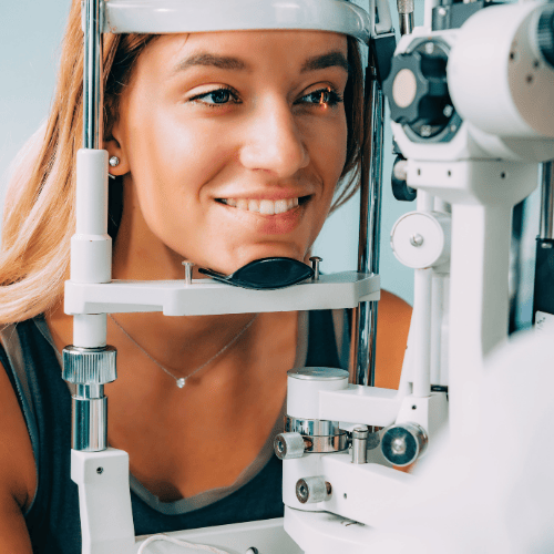 Woman having an eye exam with a slit lamp machine, smiling.
