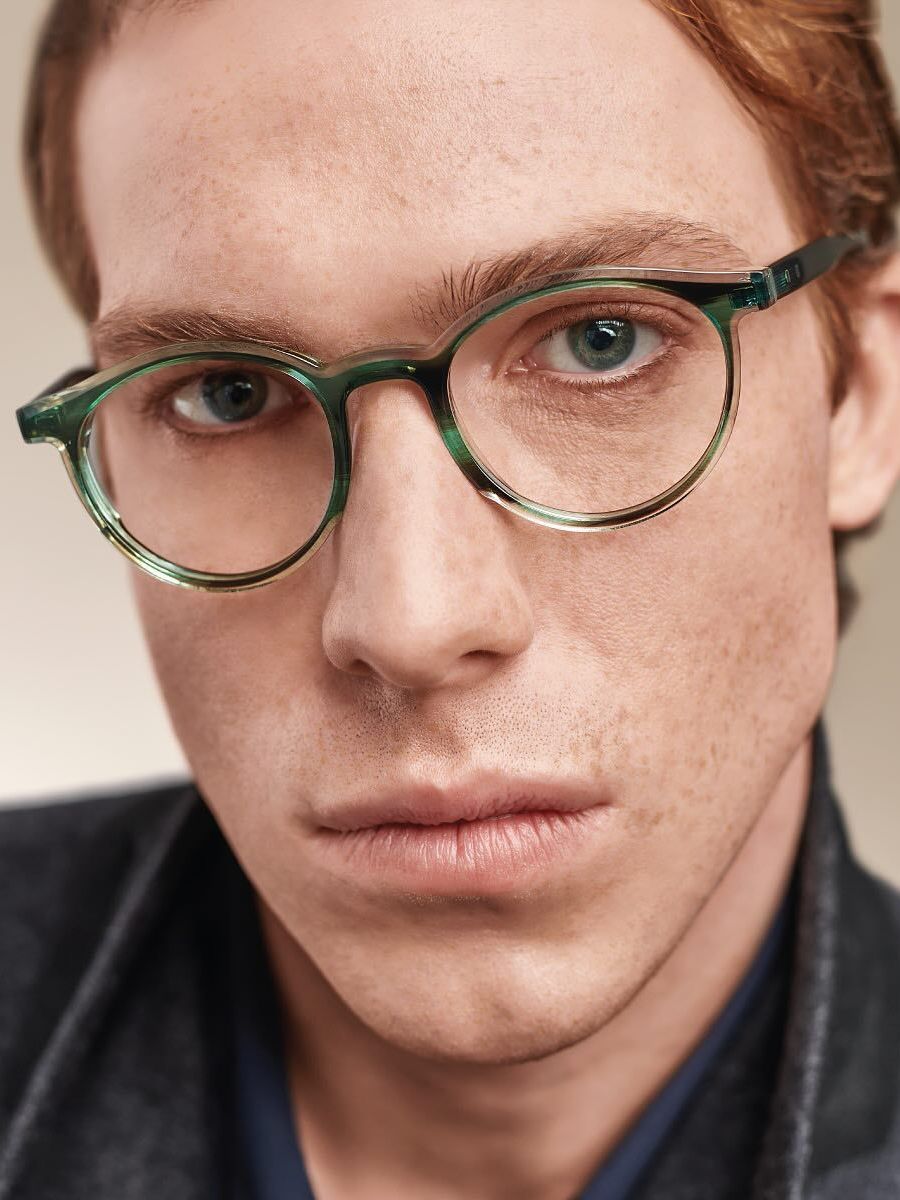 A close up of a man wearing glasses and a leather jacket