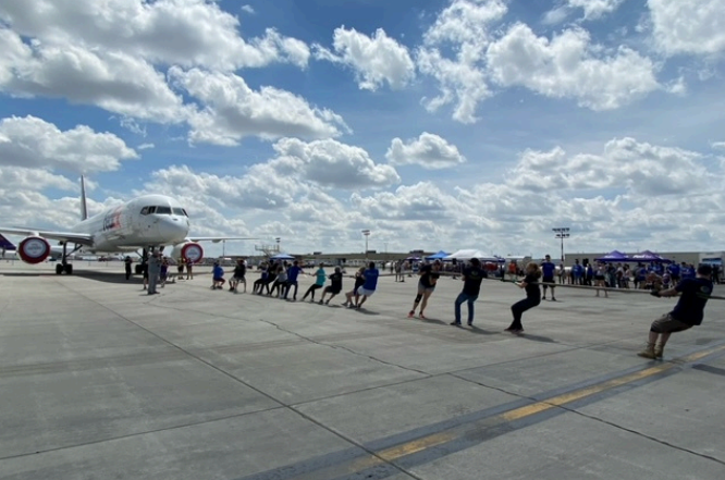 A group of people are standing on a runway next to an airplane.