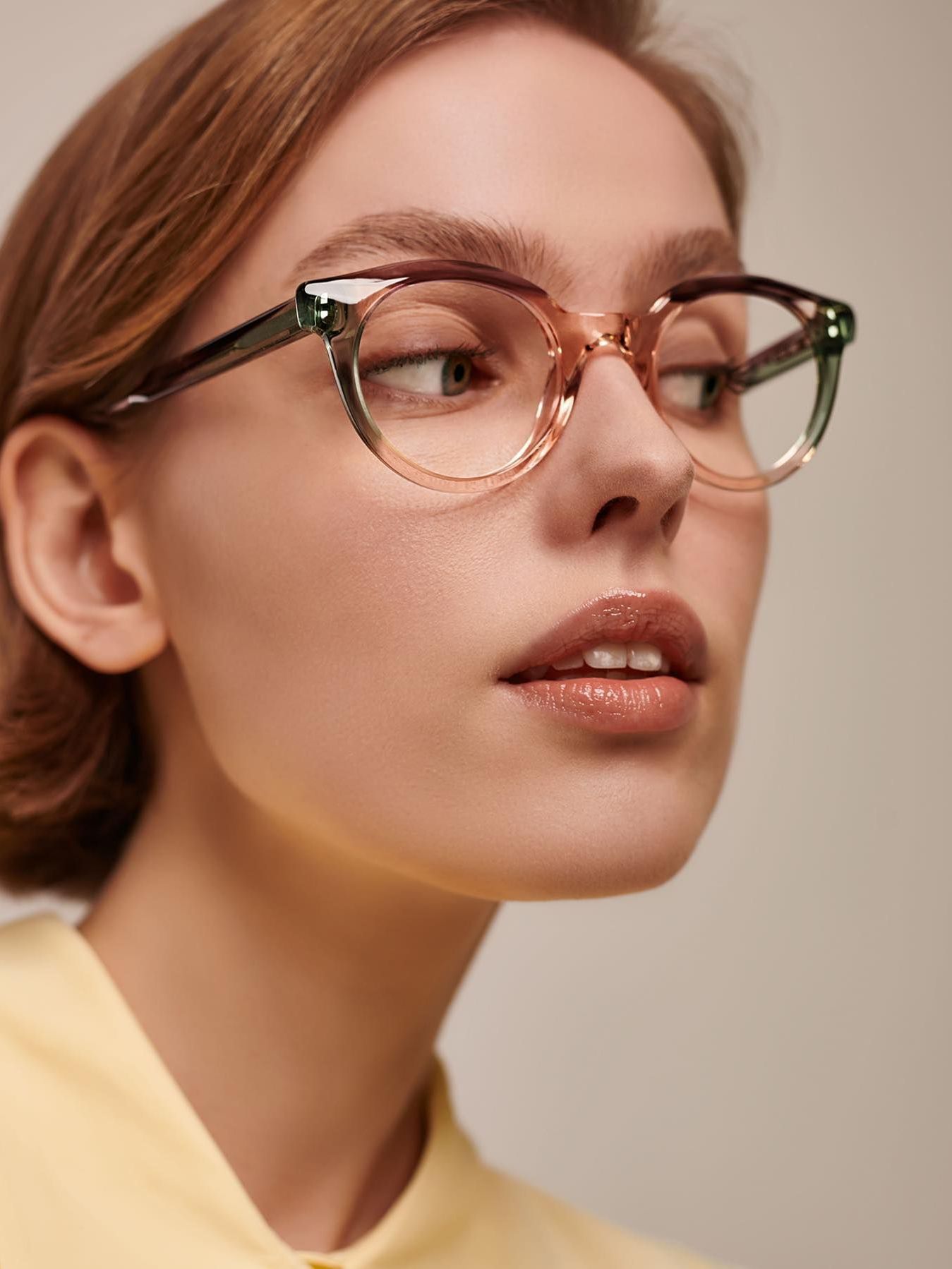 A close up of a woman wearing glasses and a yellow shirt