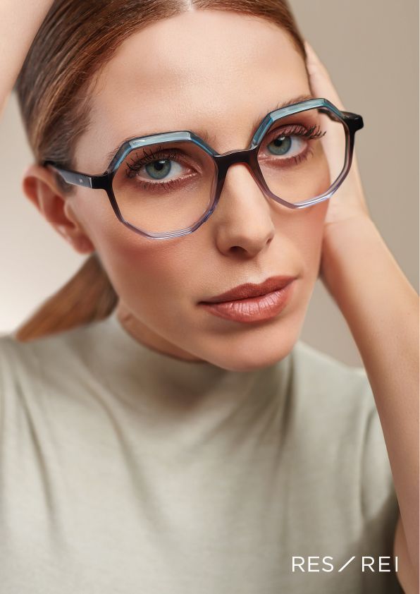 A woman wearing acetate glasses is holding her hand to her face.