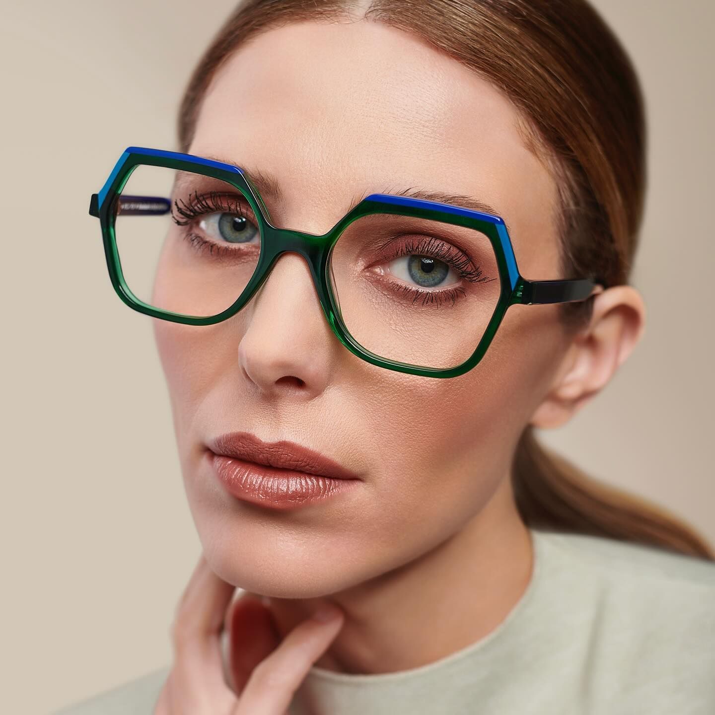 A close up of a woman wearing green and blue glasses