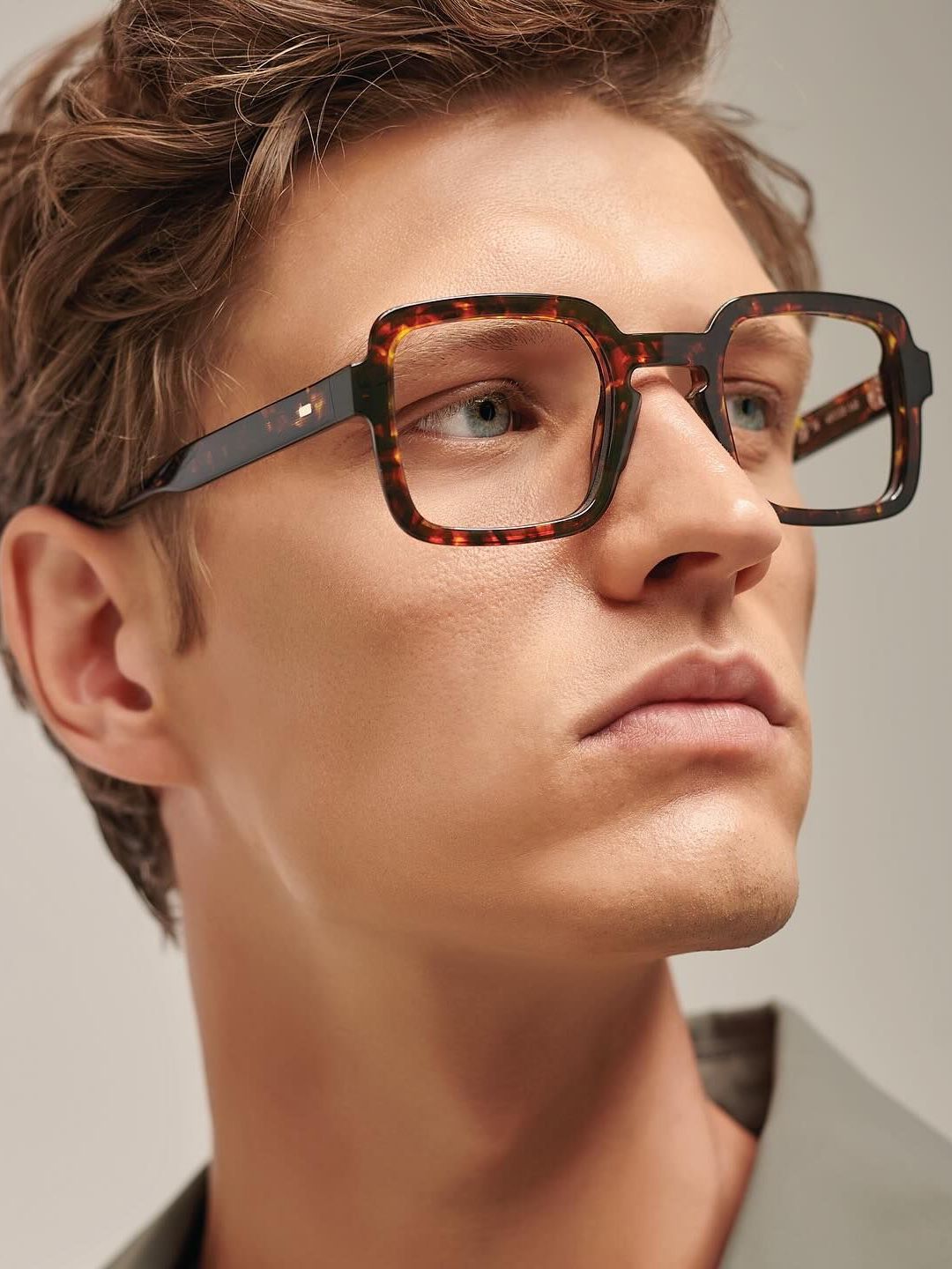 A close up of a man wearing glasses with a square frame