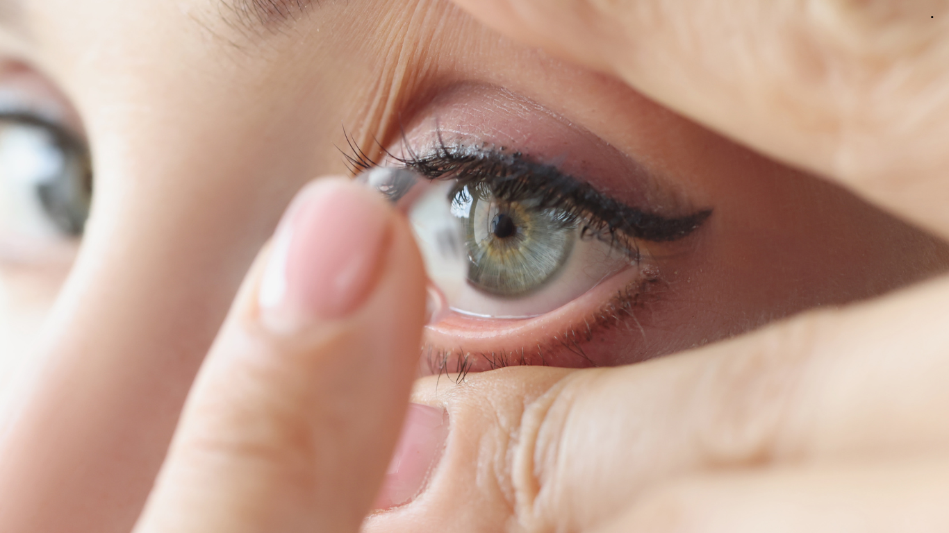 A woman is putting a contact lens in her eye.