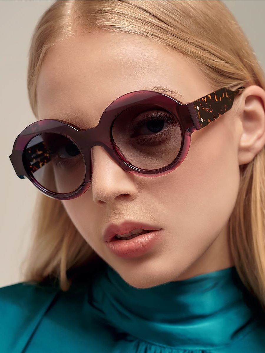 A close up of a woman wearing sunglasses and a blue shirt