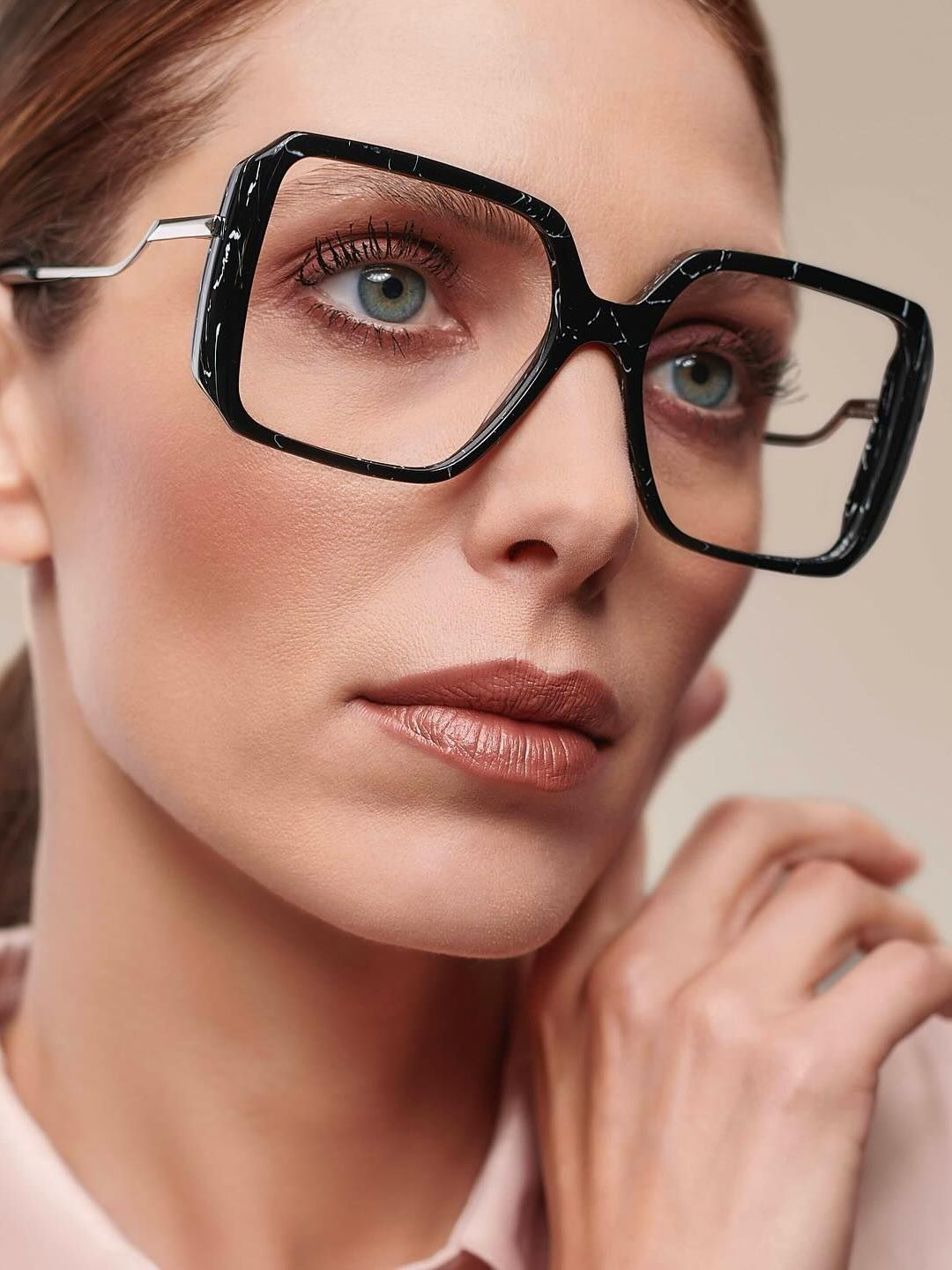 A close up of a woman wearing glasses and a pink shirt