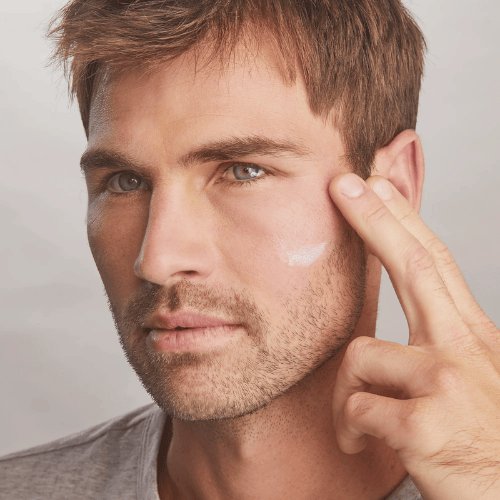 A man with a beard is applying cream to his face