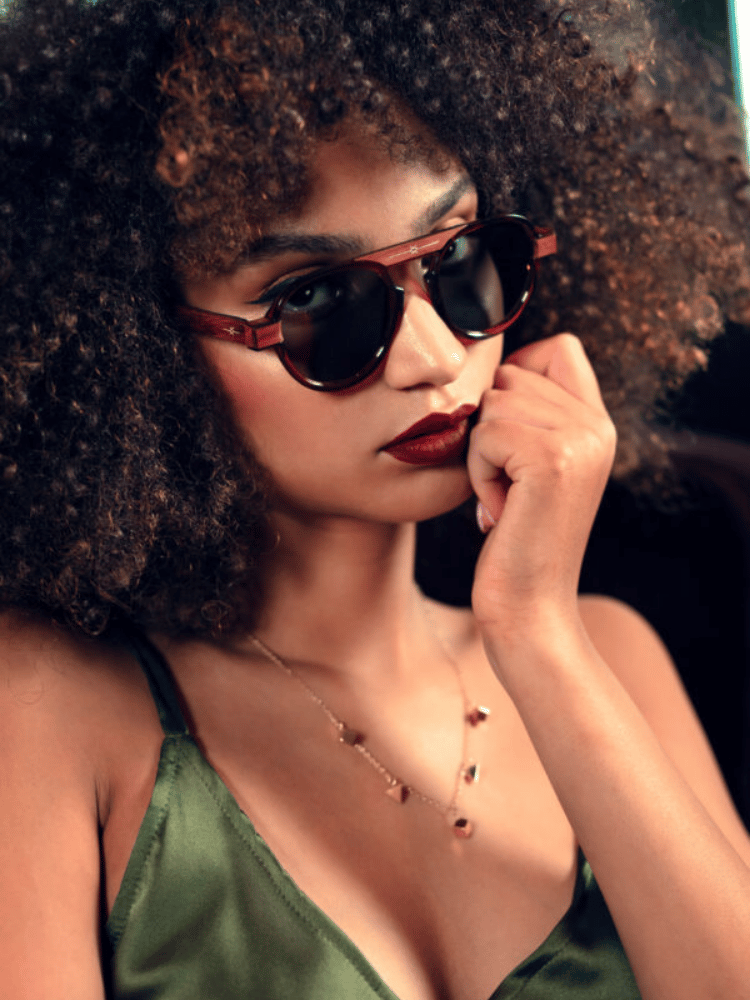 A woman with an afro wearing sunglasses and a necklace.