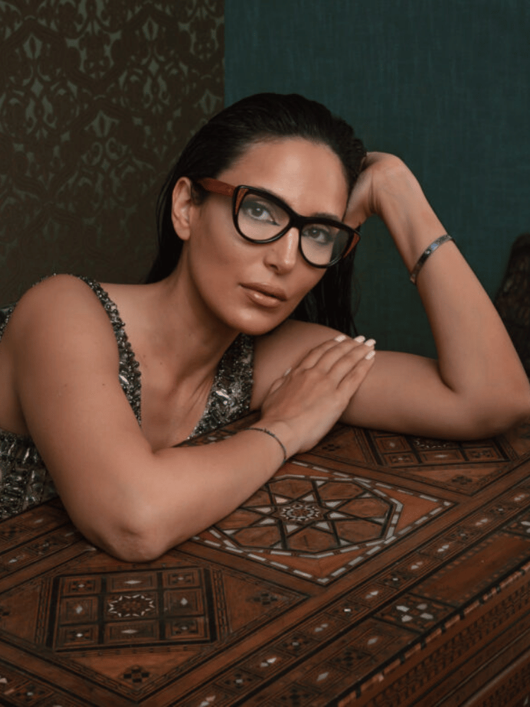 A woman wearing glasses is laying on a wooden table