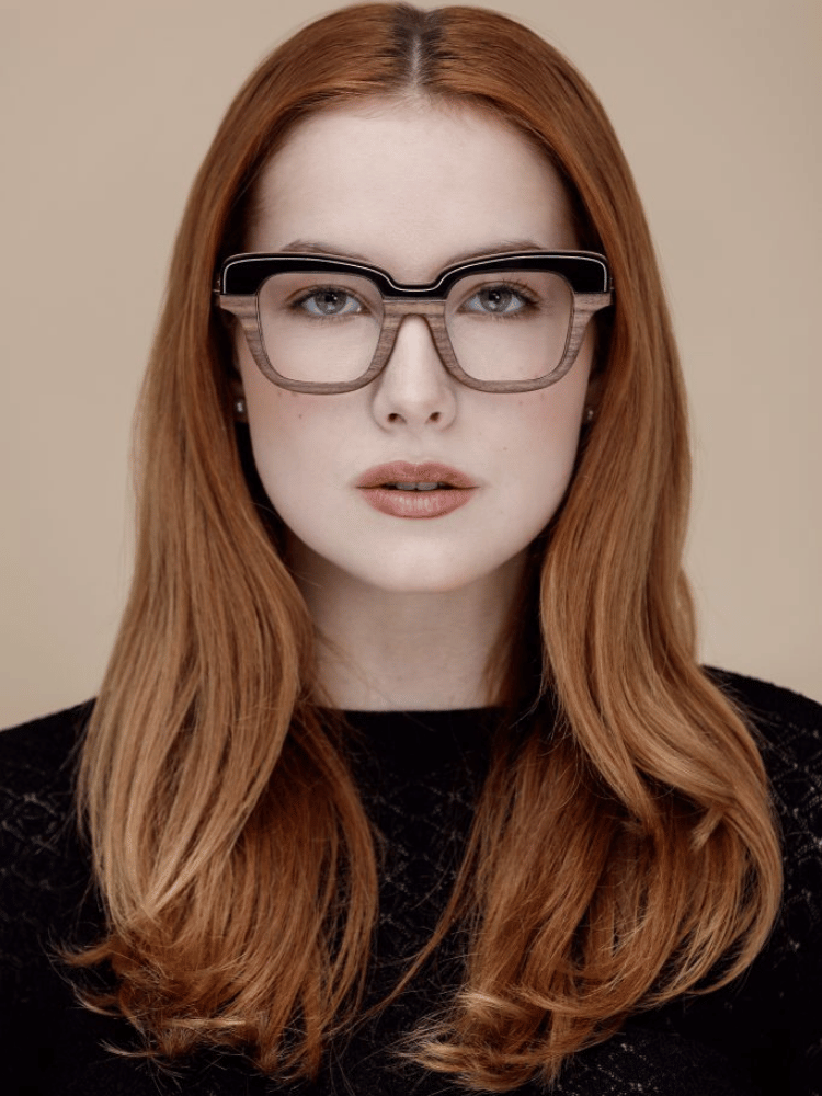 A woman wearing glasses and a black shirt is looking at the camera.