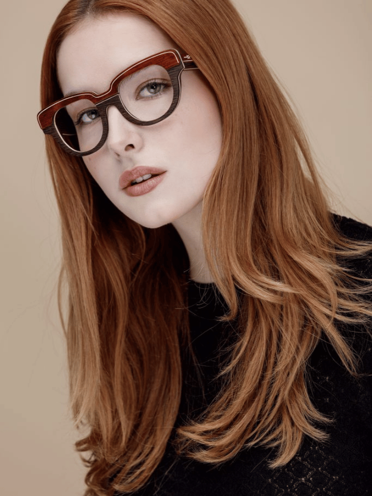 A woman with long red hair wearing glasses and a black sweater