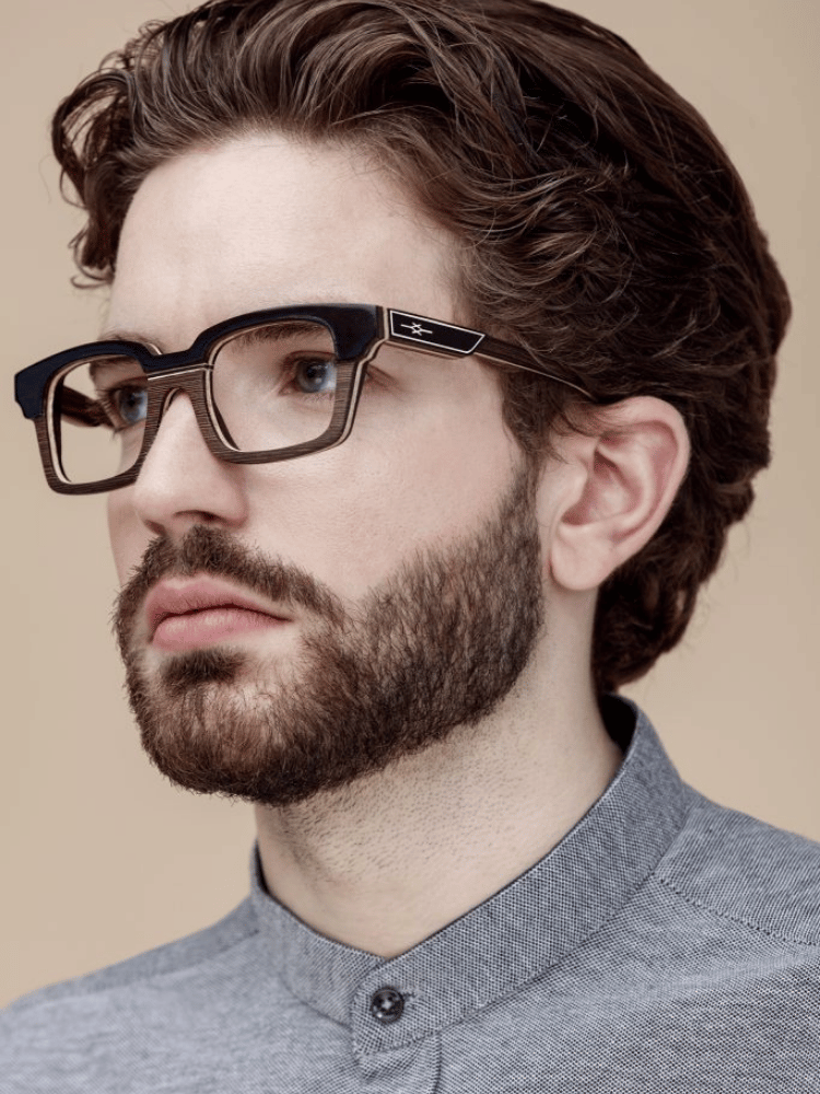 A man with a beard wearing glasses and a grey shirt