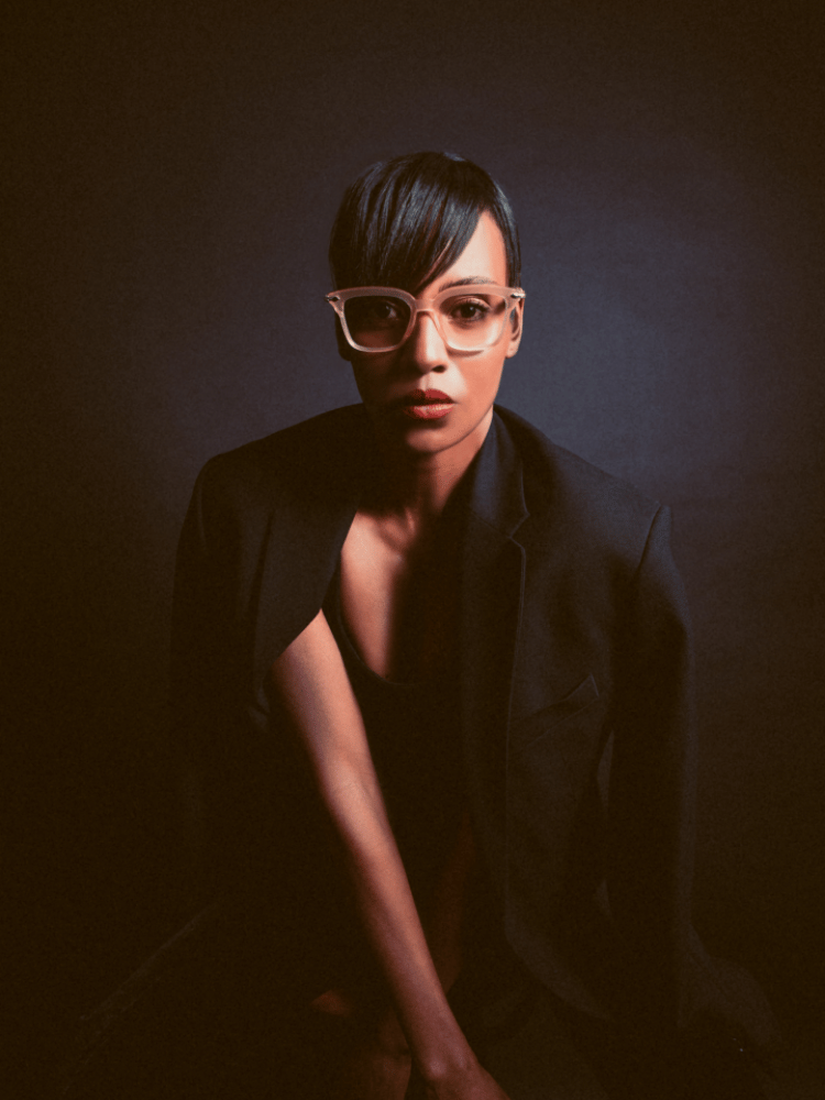 A woman wearing glasses and a black jacket is posing for a picture.