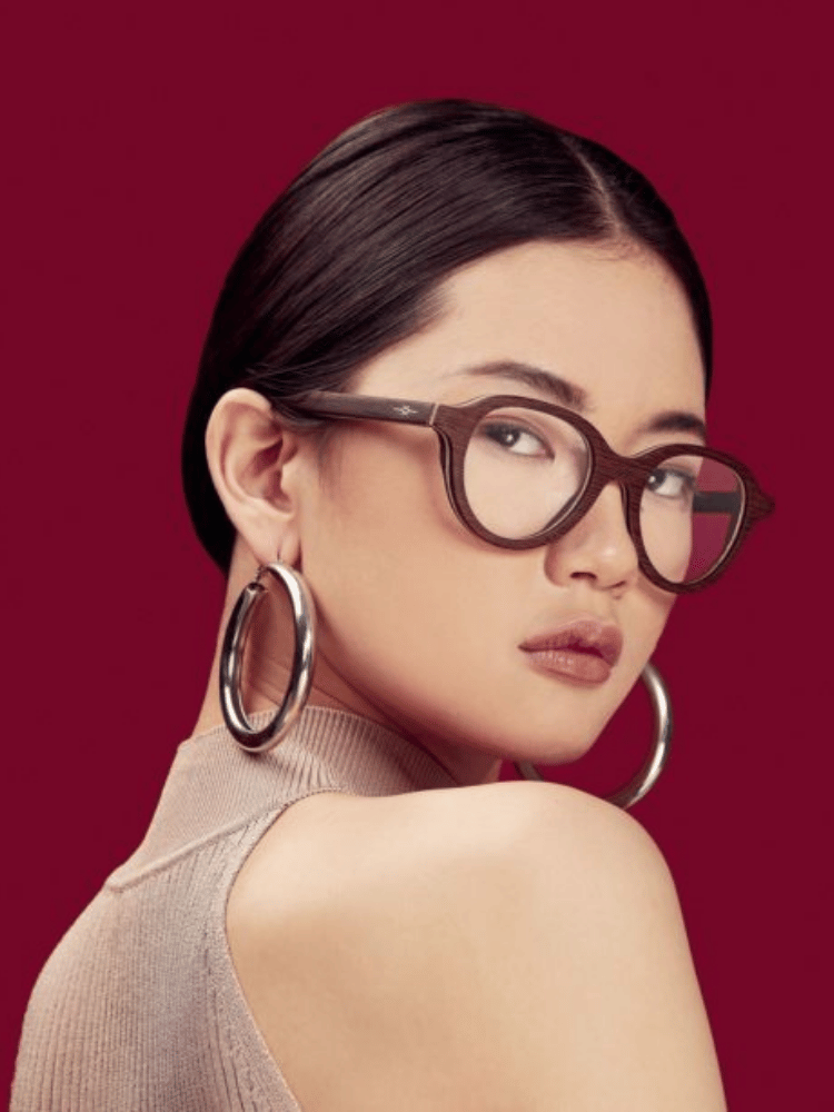 A woman wearing glasses and hoop earrings looks over her shoulder