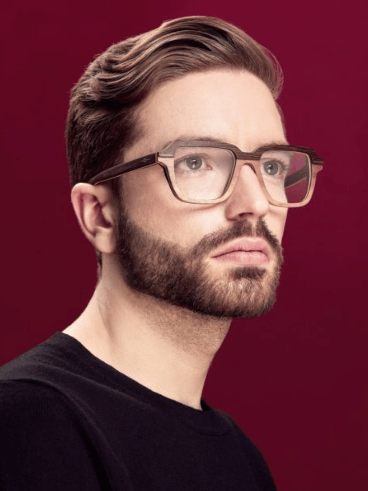 A man with a beard and glasses is wearing a black shirt.