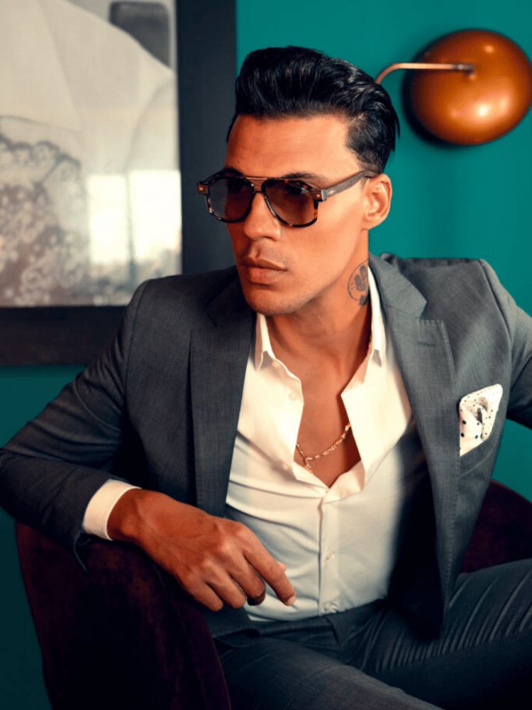 A man in a suit and sunglasses is sitting in a chair