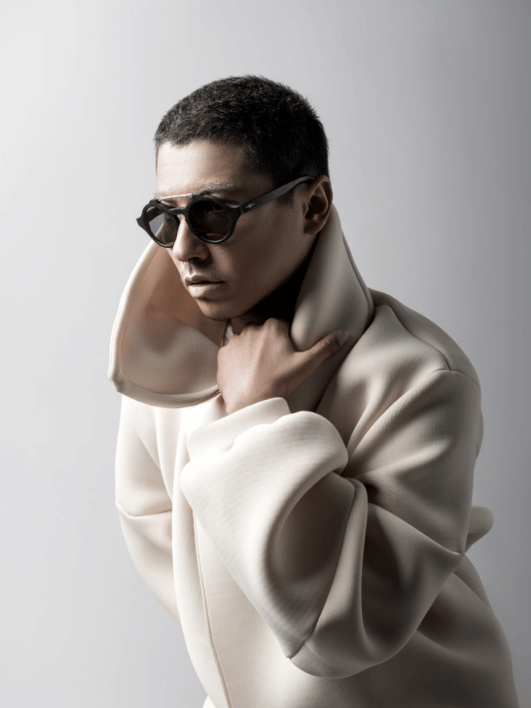 A man wearing sunglasses and a white coat