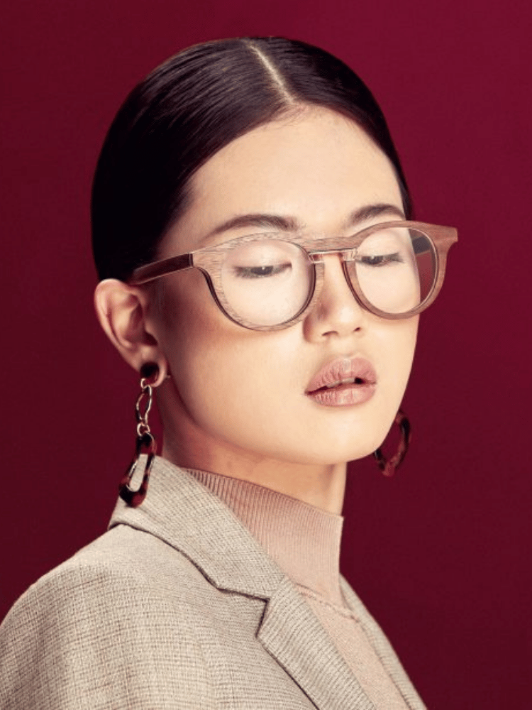 A woman wearing glasses and earrings with her eyes closed