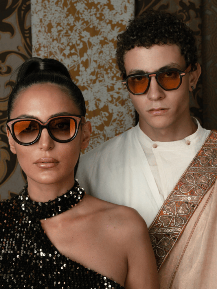 A man and a woman wearing sunglasses are standing next to each other.