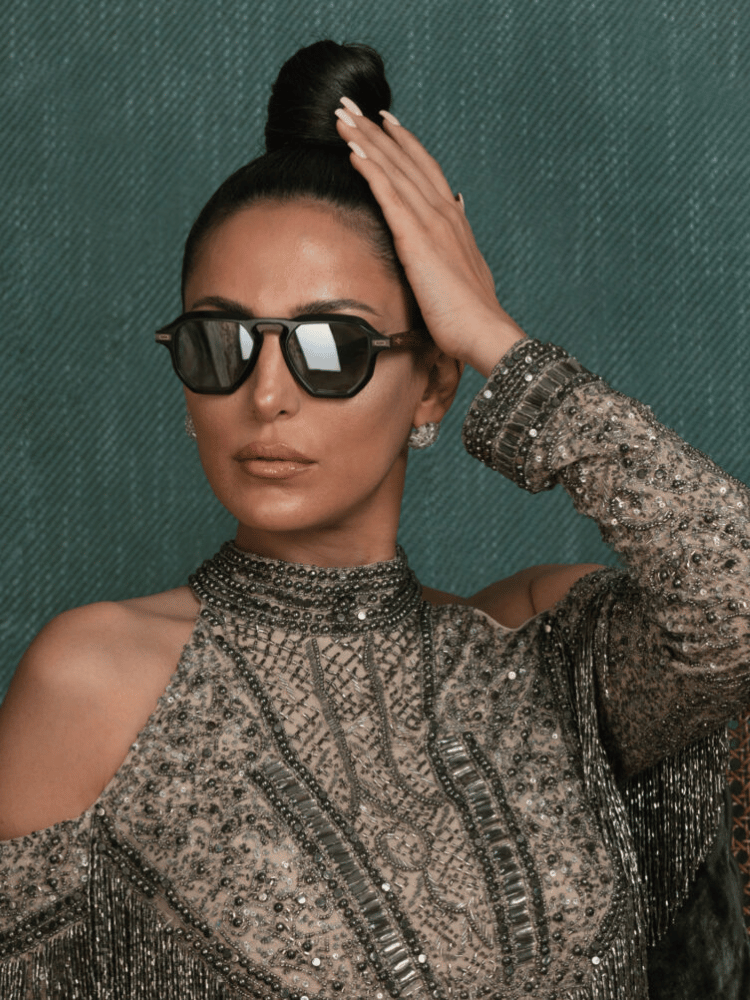 A woman wearing sunglasses holds her hair in a bun
