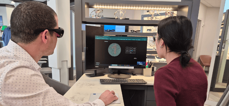 Two people looking at a computer screen displaying a circular diagram in an office setting.