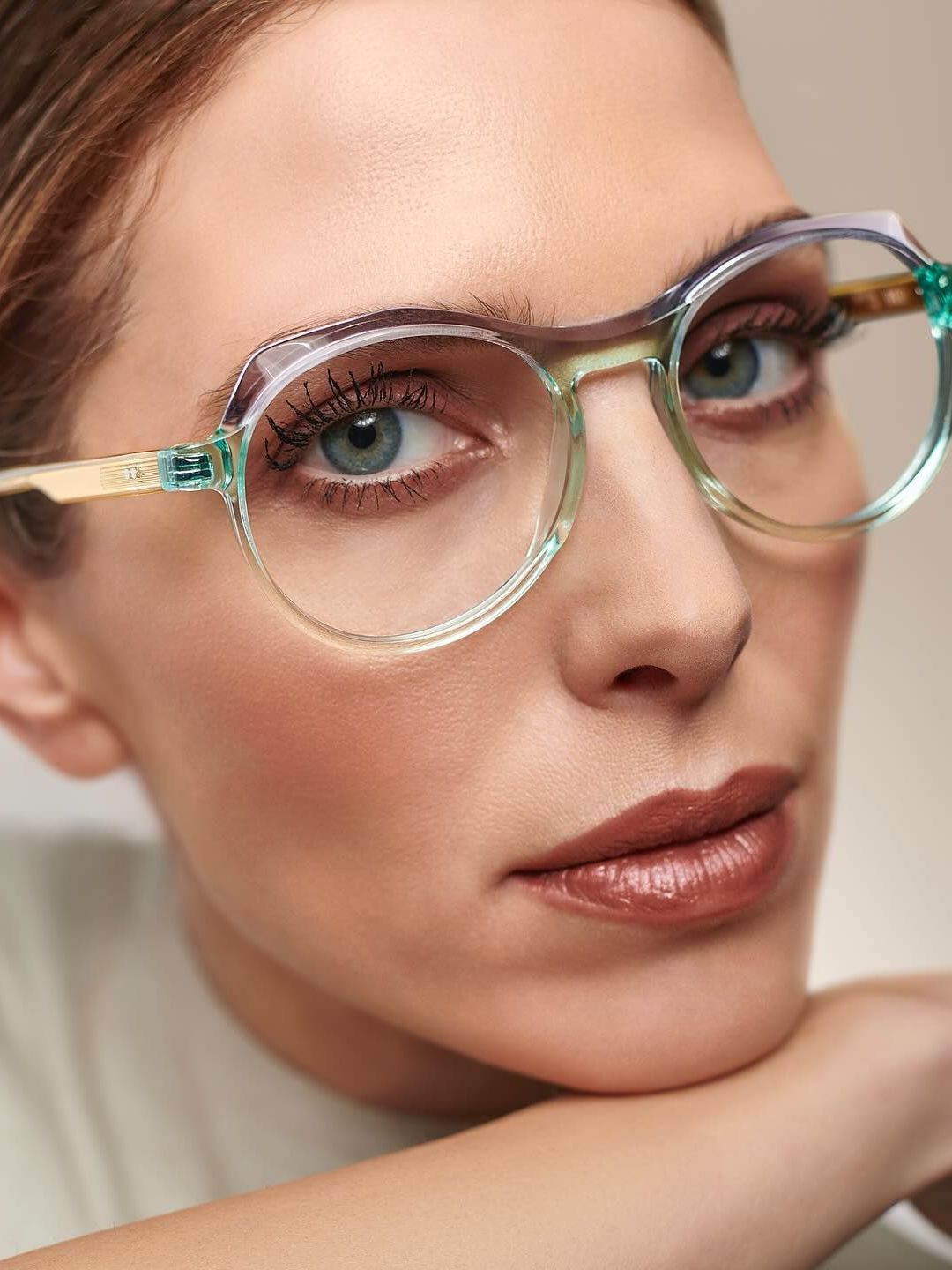 A close up of a woman wearing glasses with her hand on her chin.