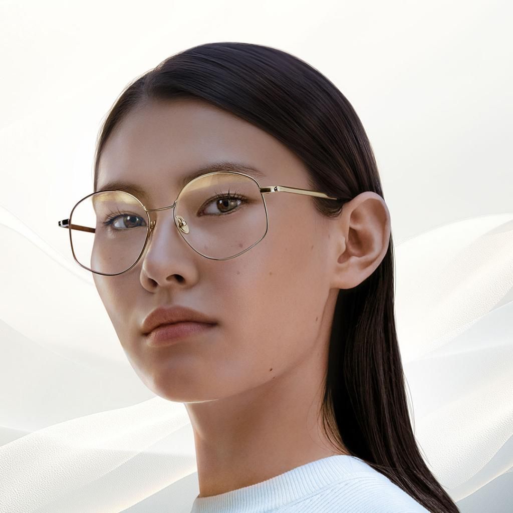 A woman wearing glasses and a white shirt is looking at the camera.