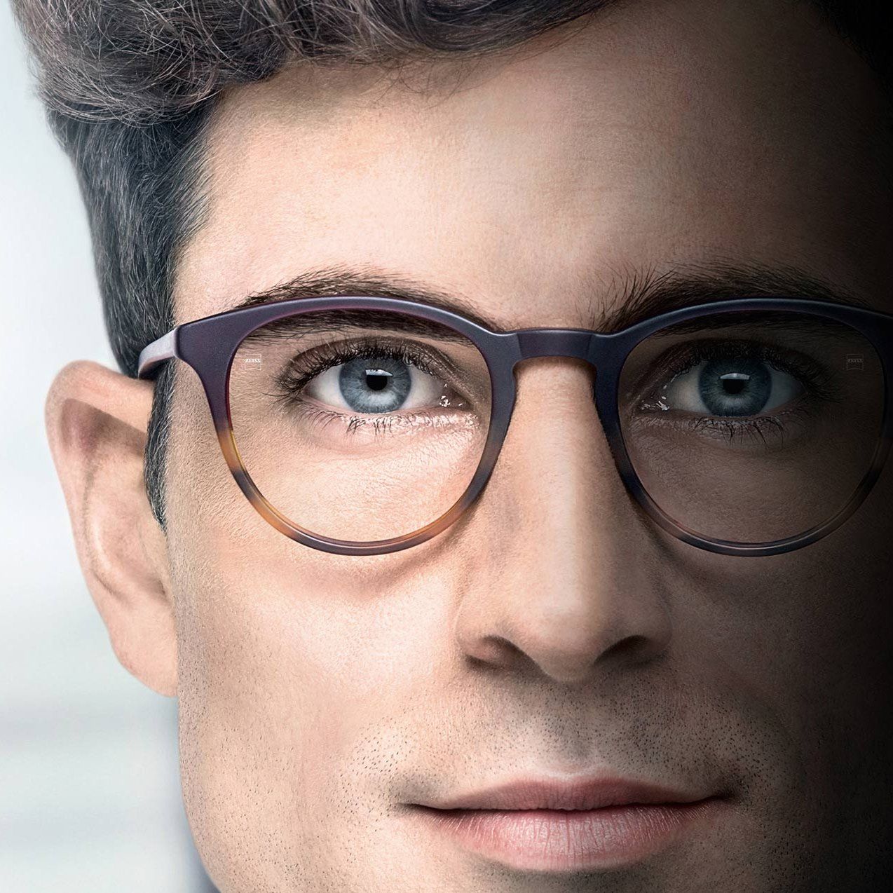 A close up of a man wearing glasses with blue eyes.