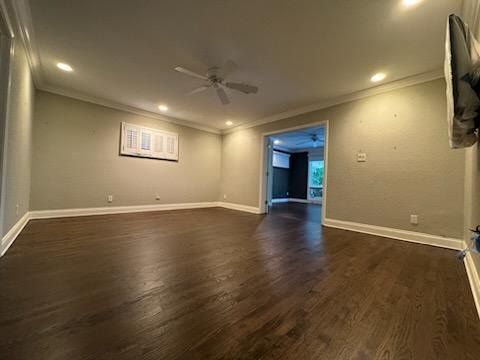 Empty living room with dark hardwood floors, beige walls, recessed lighting, and an open doorway to a blue-lit area