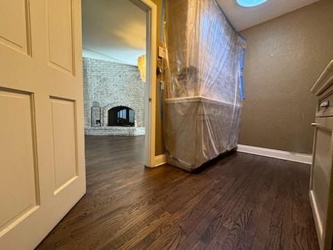 Hallway with hardwood floors, beige walls, and a large plastic-wrapped item near an open doorway
