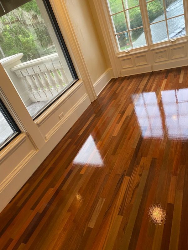 Sunlit hardwood floor in an empty room with French doors and a sliding glass door.