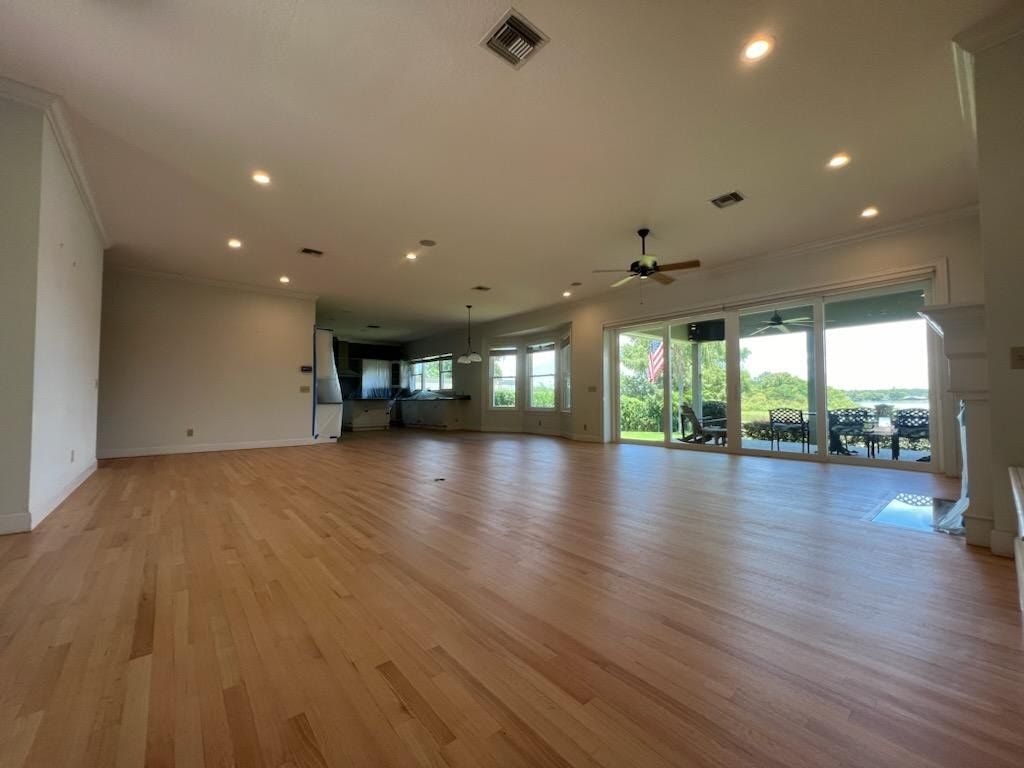 Spacious empty living room with hardwood floors, recessed lights, and large sliding glass doors to a patio and greenery