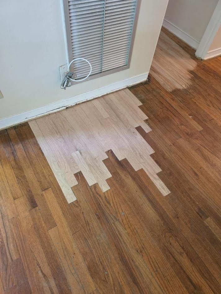White residue spilled on a hardwood floor by a doorway and vent.