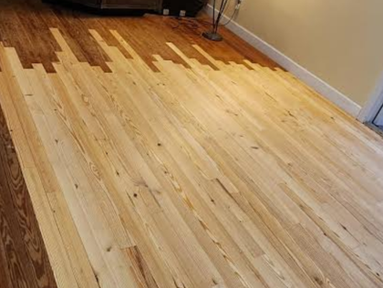 Partially refinished hardwood floor with light and dark wood tones in a room