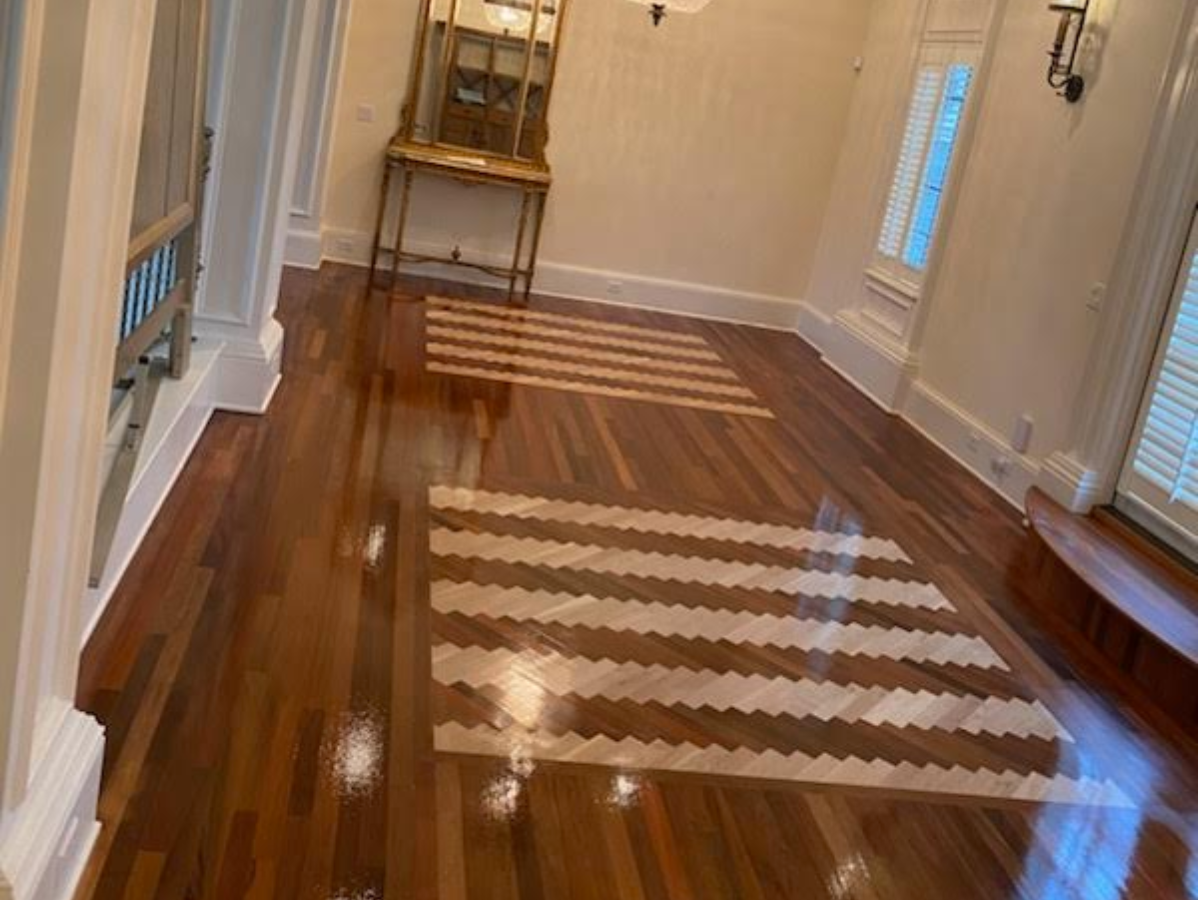 Partially refinished hardwood floor with light and dark wood tones in a room
