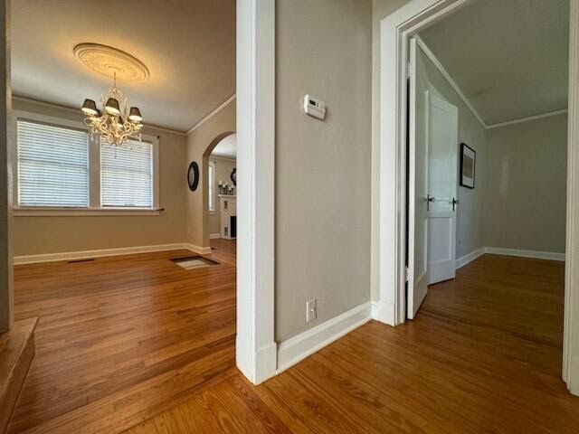 Empty living room and hallway with hardwood floors, white walls, and a ceiling fan.