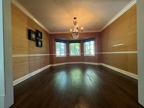 Empty formal dining room with wood floors, tan walls, chandelier, and bay windows at the far end