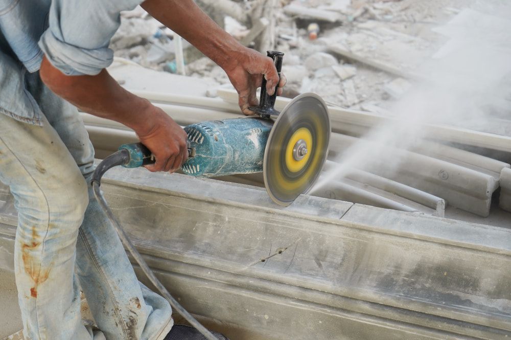 A Man Is Cutting A Piece Of Concrete With A Grinder — Accu-Cut In Manunda, QLD