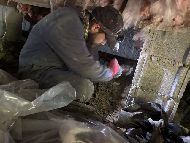 Plumber tightening a copper pipe under a sink with water leaking onto the floor
