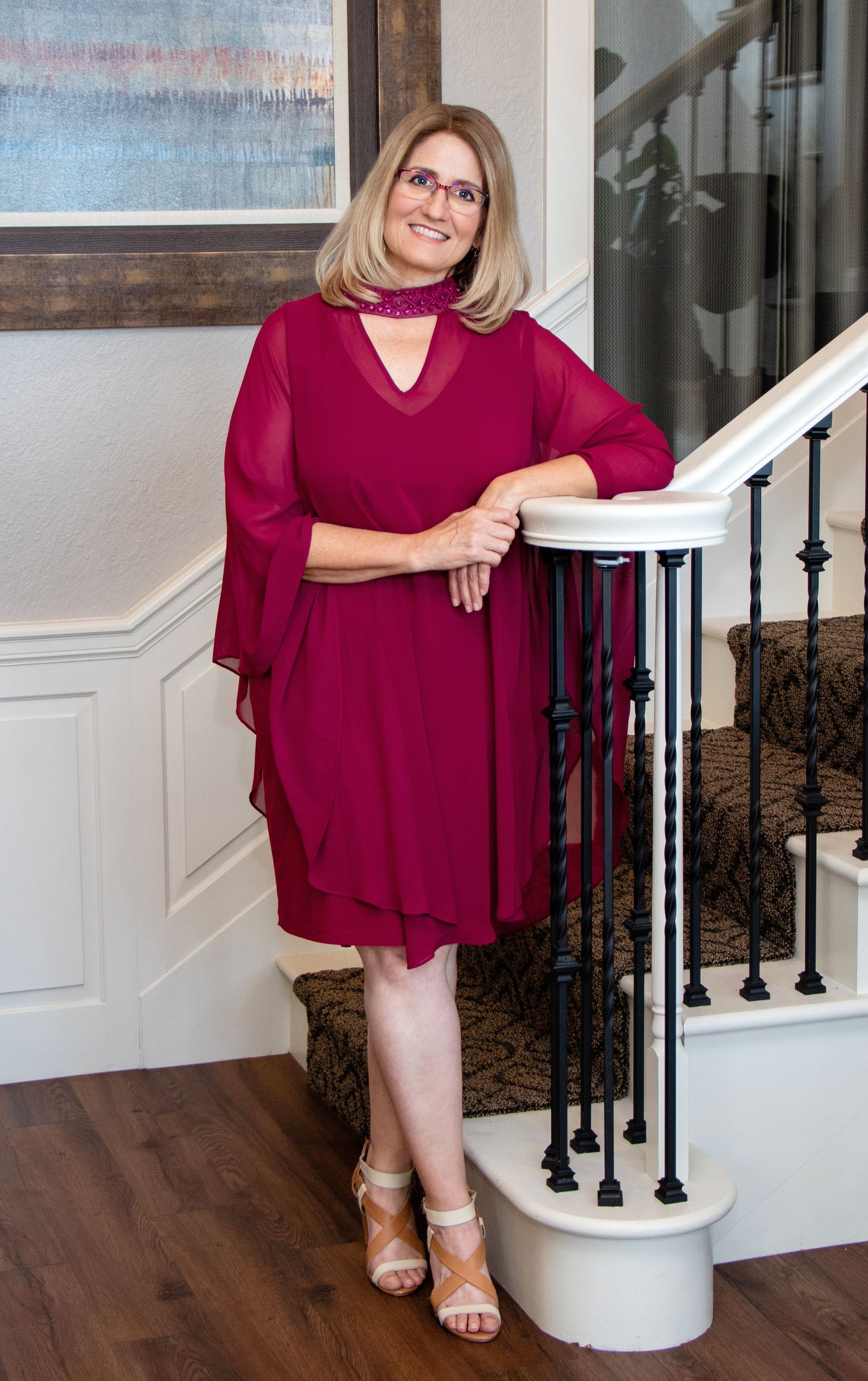 A woman in a red dress is standing on a set of stairs.