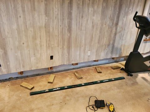 A bicycle is sitting on the floor in a basement next to a wooden wall.