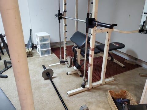 A gym with a bench , barbells , and a mirror.