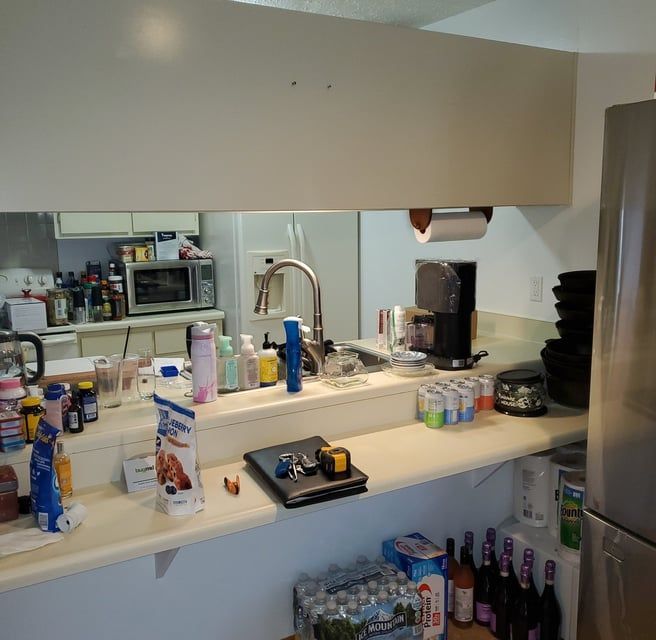 A kitchen counter with bottles and cans including one that says ' coca cola ' on it