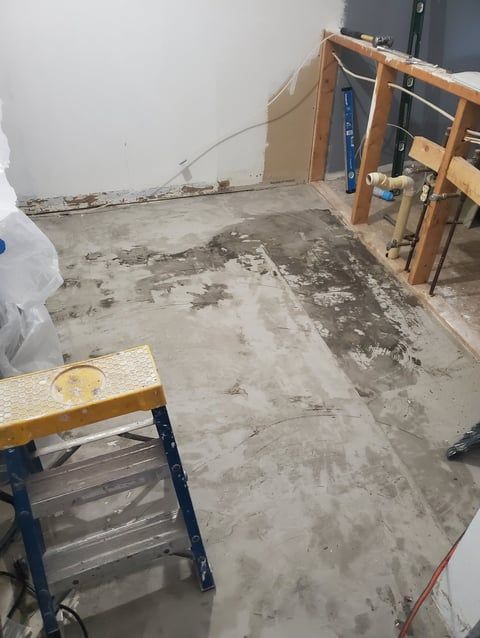 A ladder is sitting on the floor of a room under construction.