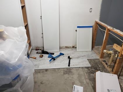 A room with a hammer , tape measure , and other tools on the floor.