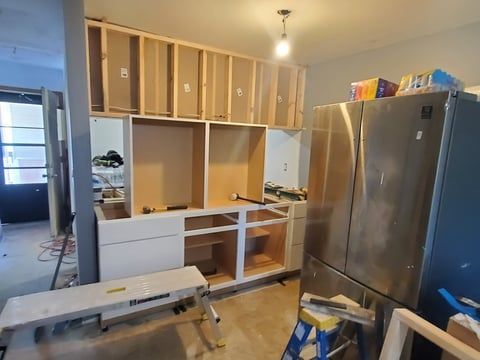A kitchen under construction with stainless steel appliances and wooden cabinets.
