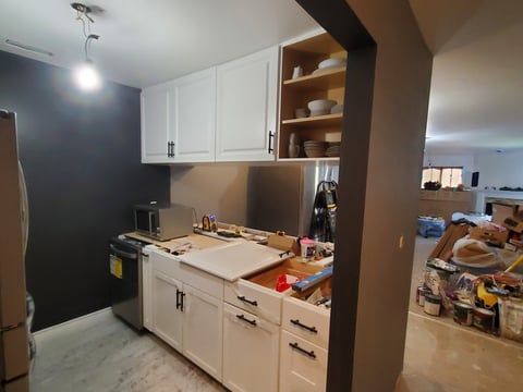 A kitchen with white cabinets and stainless steel appliances is being remodeled.