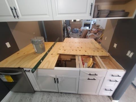 A kitchen with white cabinets and a wooden counter top